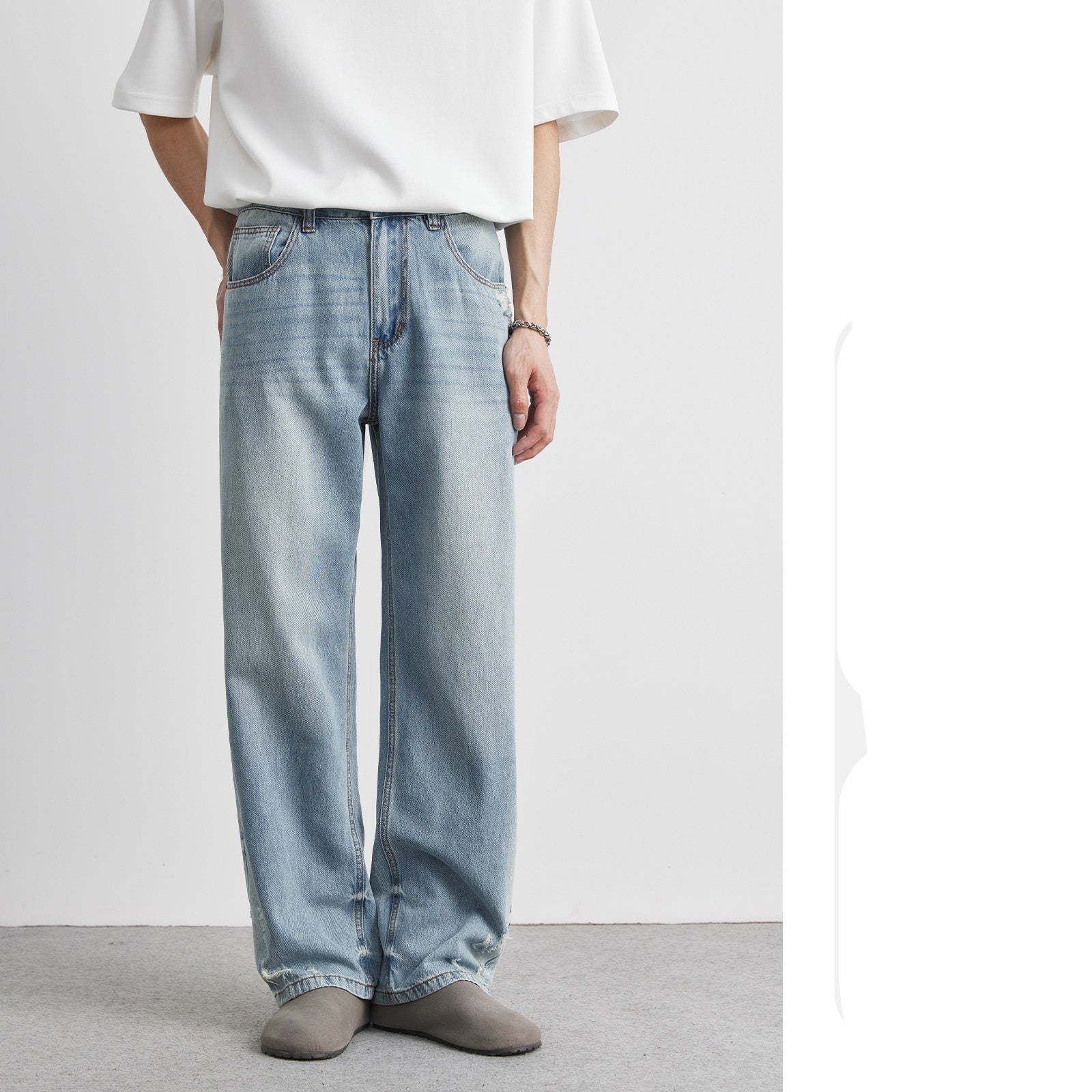 Person wearing light blue jeans and a white shirt on a plain background