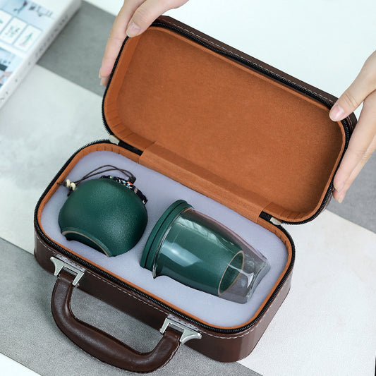 Two green ceramic cups in a brown travel case on a light gray surface.