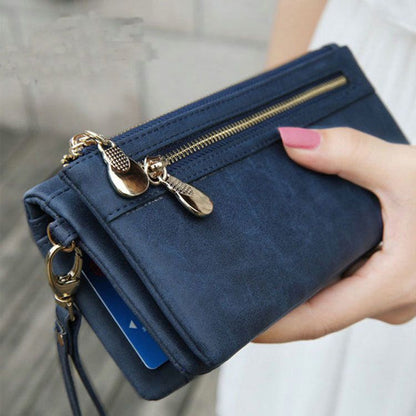 Blue wallet with gold zippers held by a hand against a neutral background
