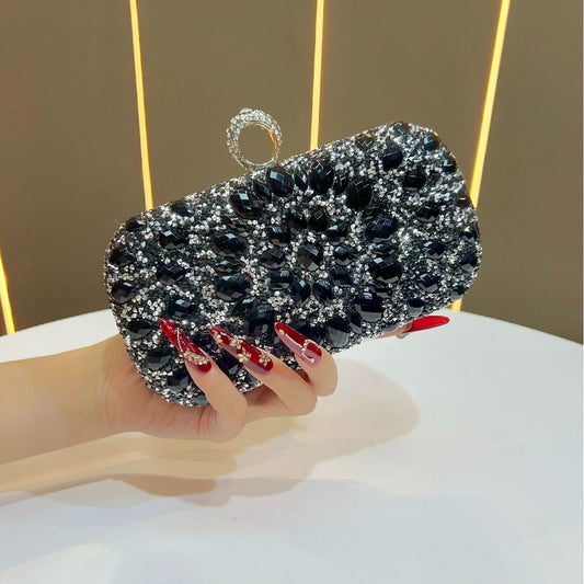 Hand holding a black and silver beaded clutch against a neutral background